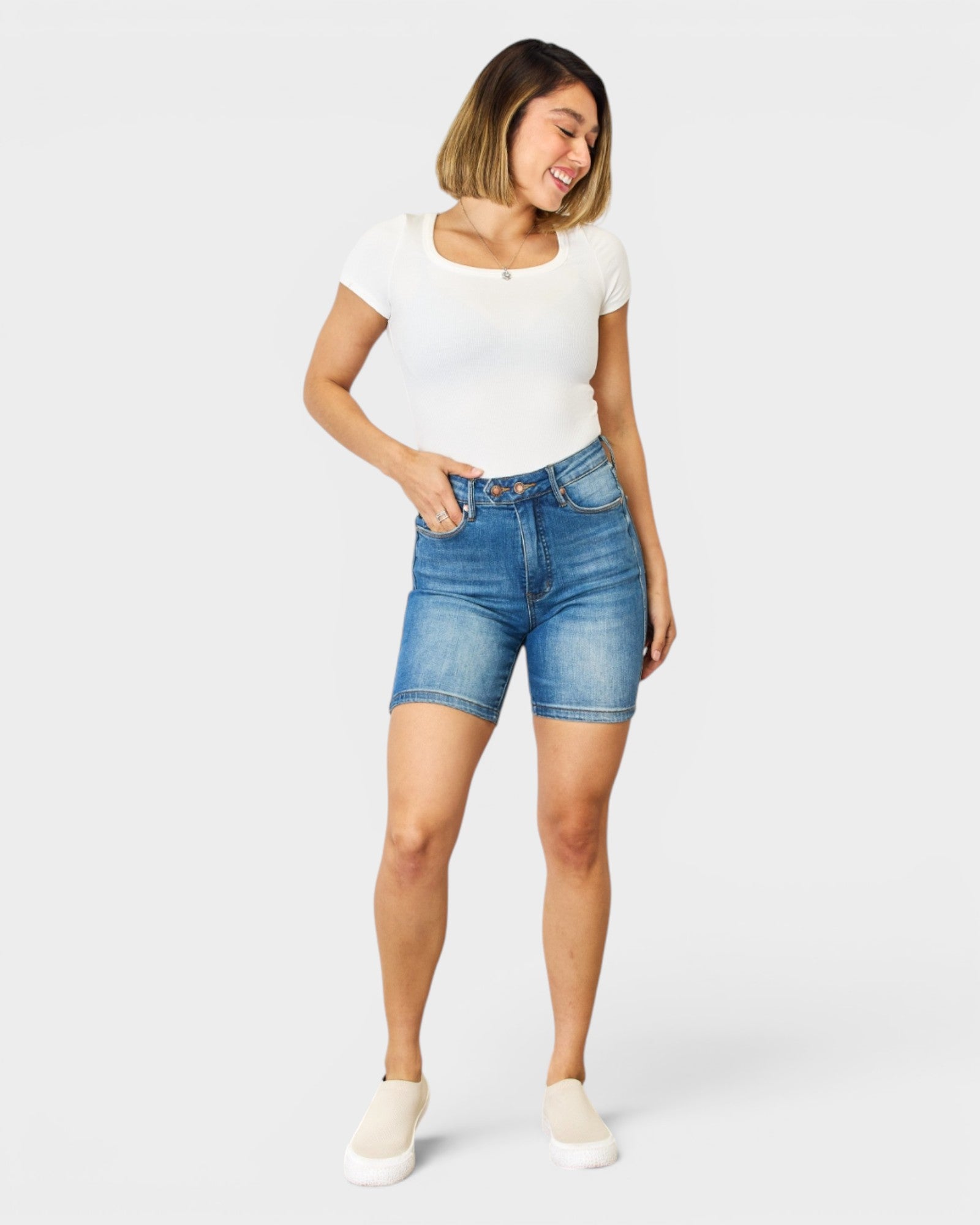 Woman wearing blue denim shorts and a white t-shirt on a white background