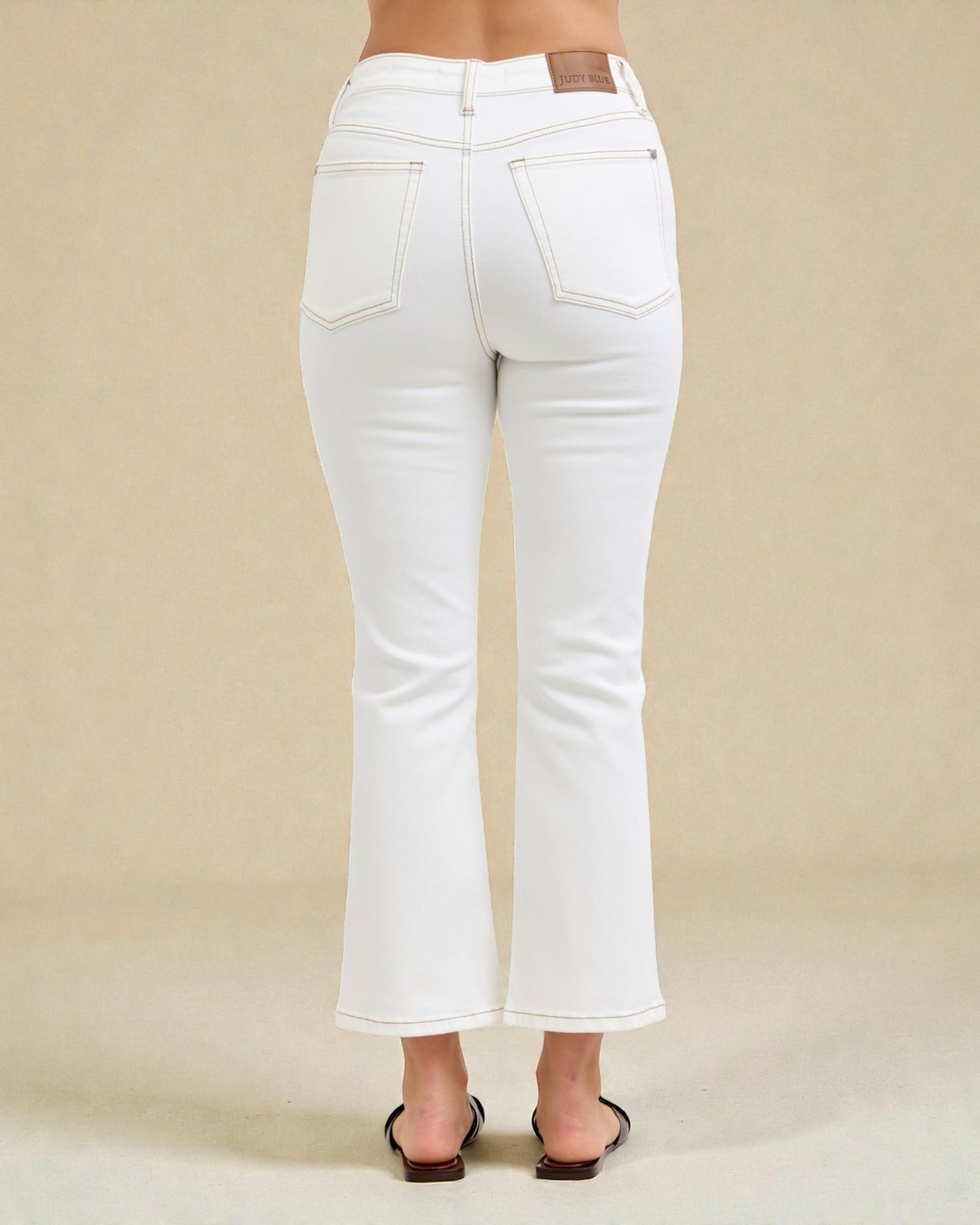 White jeans worn by a person on a beige background