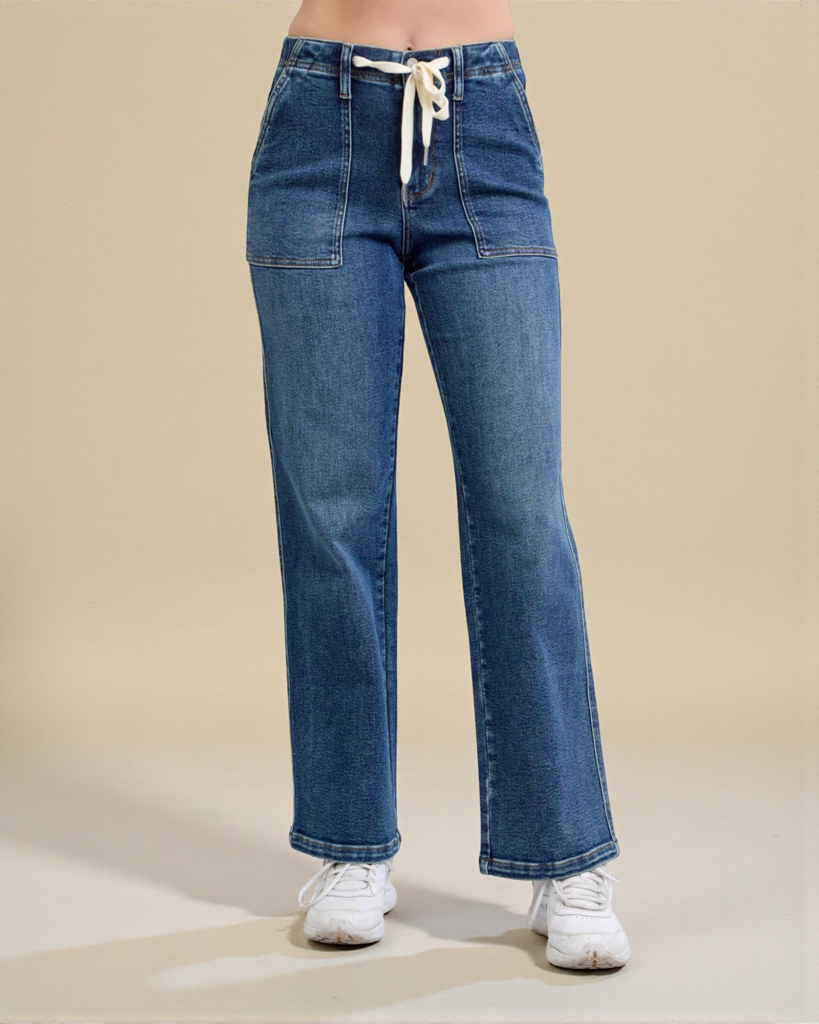 Blue jeans worn by a person on a beige background