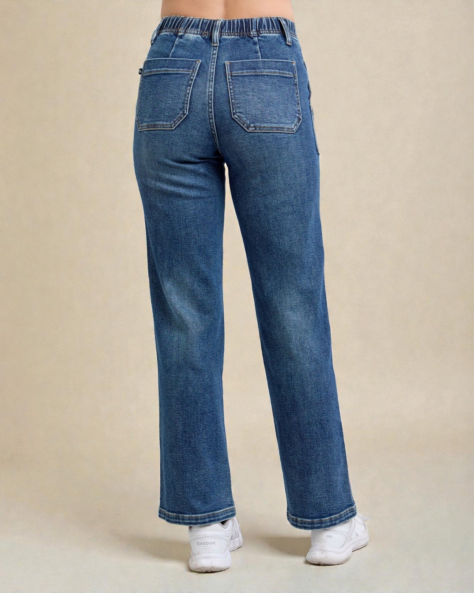 Blue jeans worn by a person on a beige background