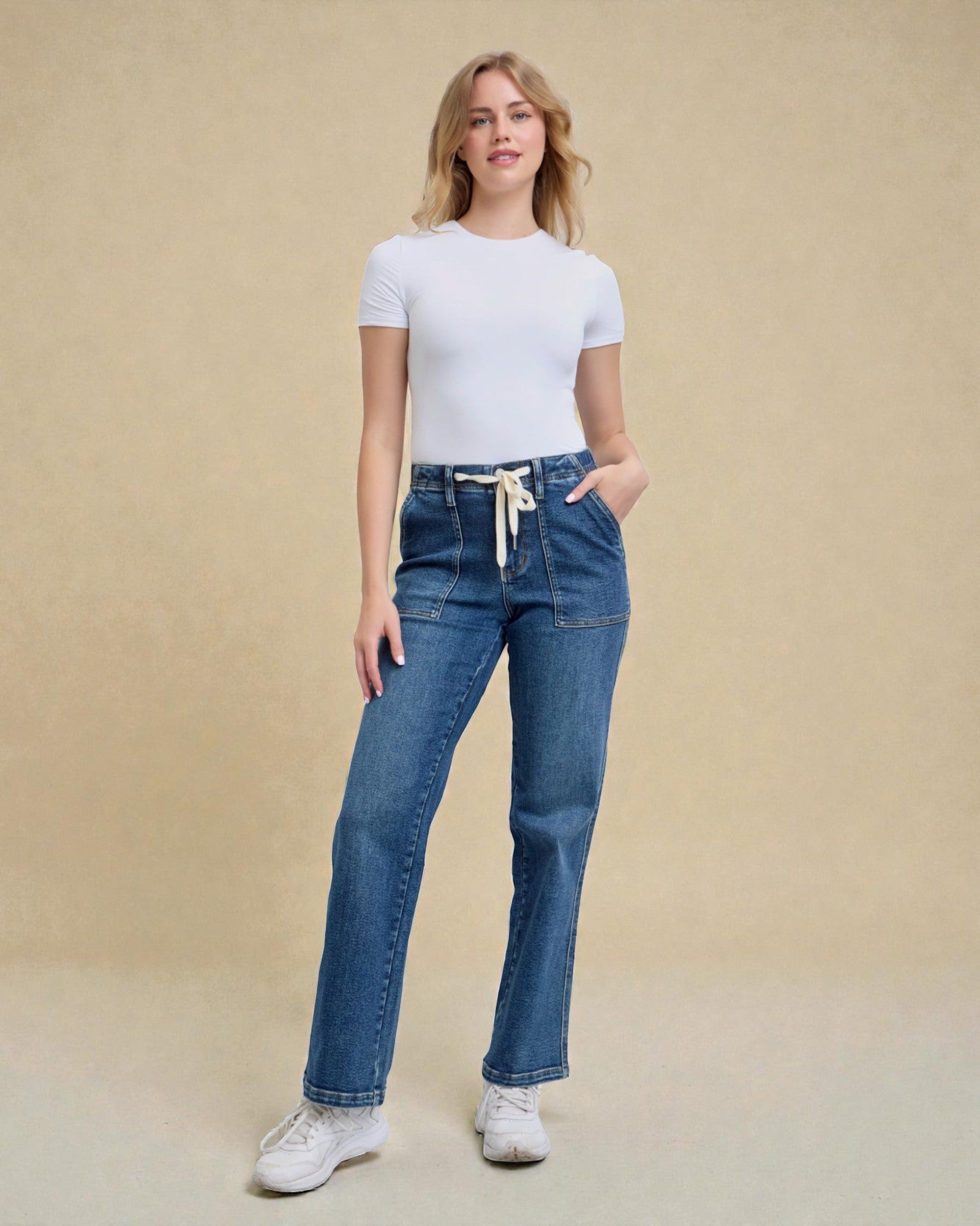 Woman wearing blue jeans and a white t-shirt on a beige background
