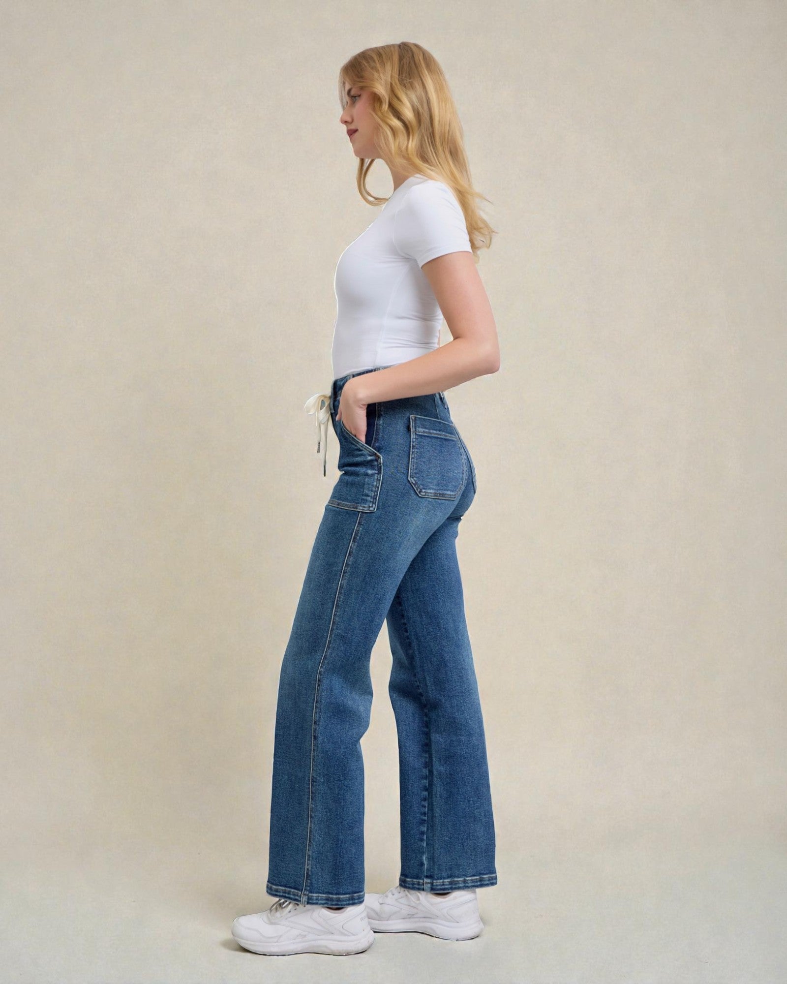 Woman wearing blue jeans and a white t-shirt on a beige background