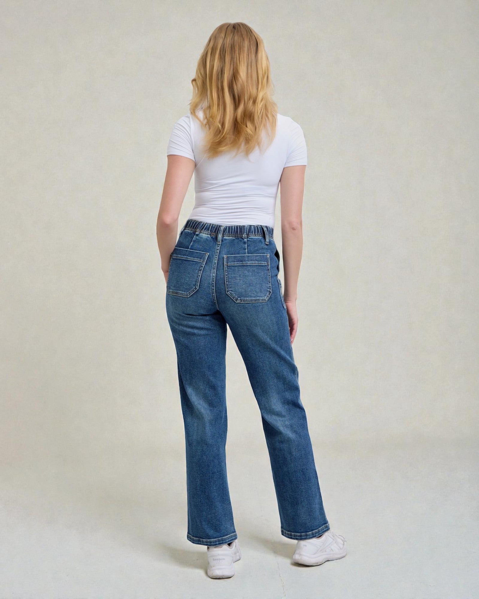 Person wearing blue jeans and a white t-shirt on a plain background