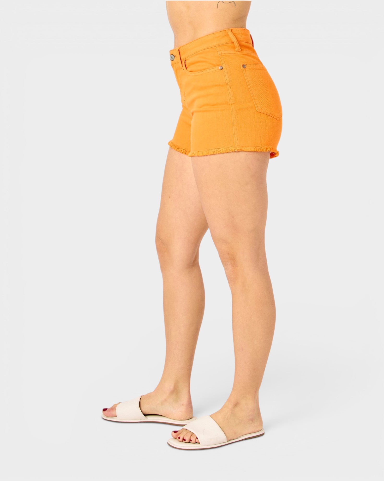 Orange denim shorts worn by a person on a white background