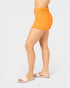 Person wearing bright orange shorts on a plain background