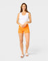 Woman wearing orange shorts and a white tank top on a light gray background
