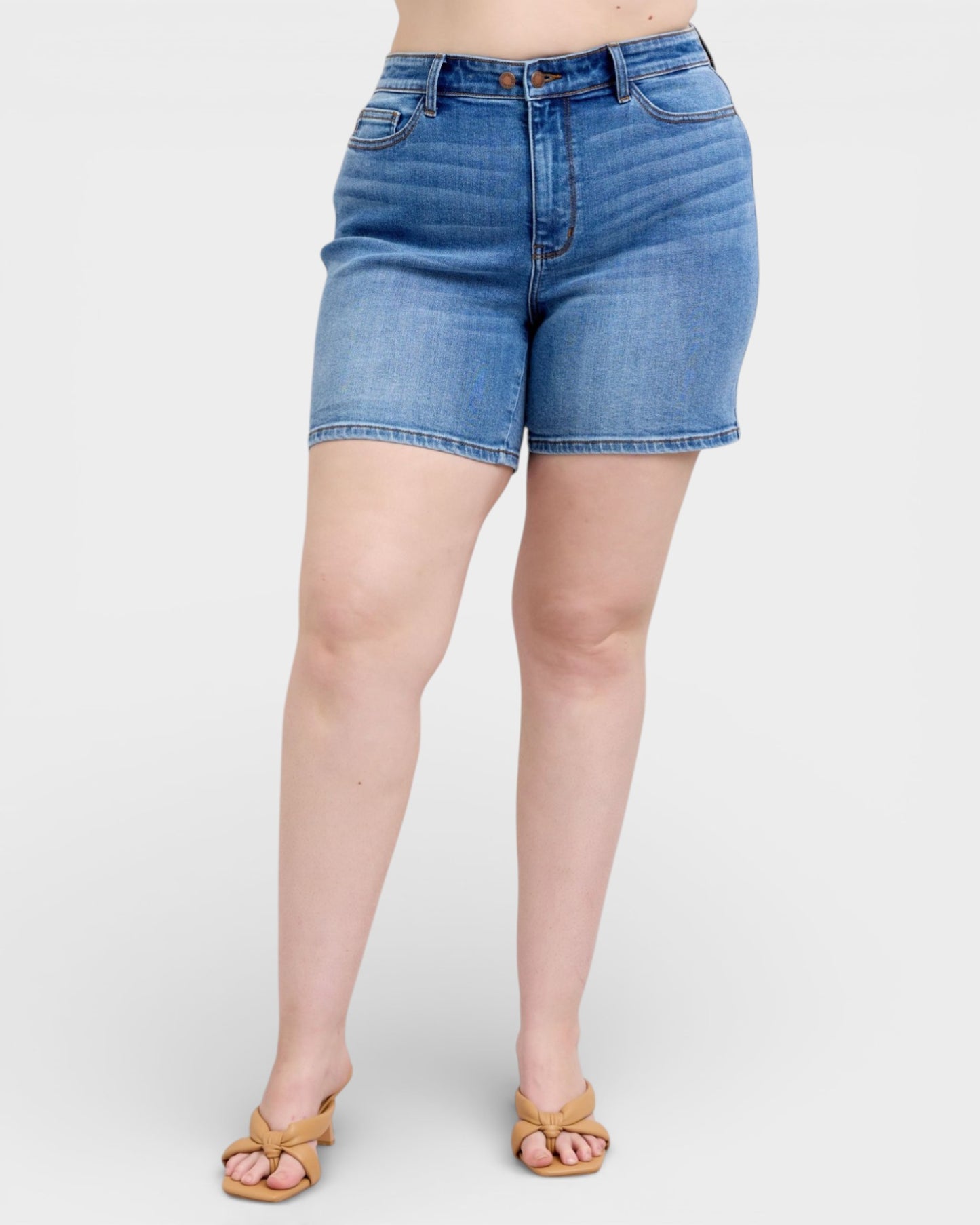 Blue denim shorts worn by a person on a white background