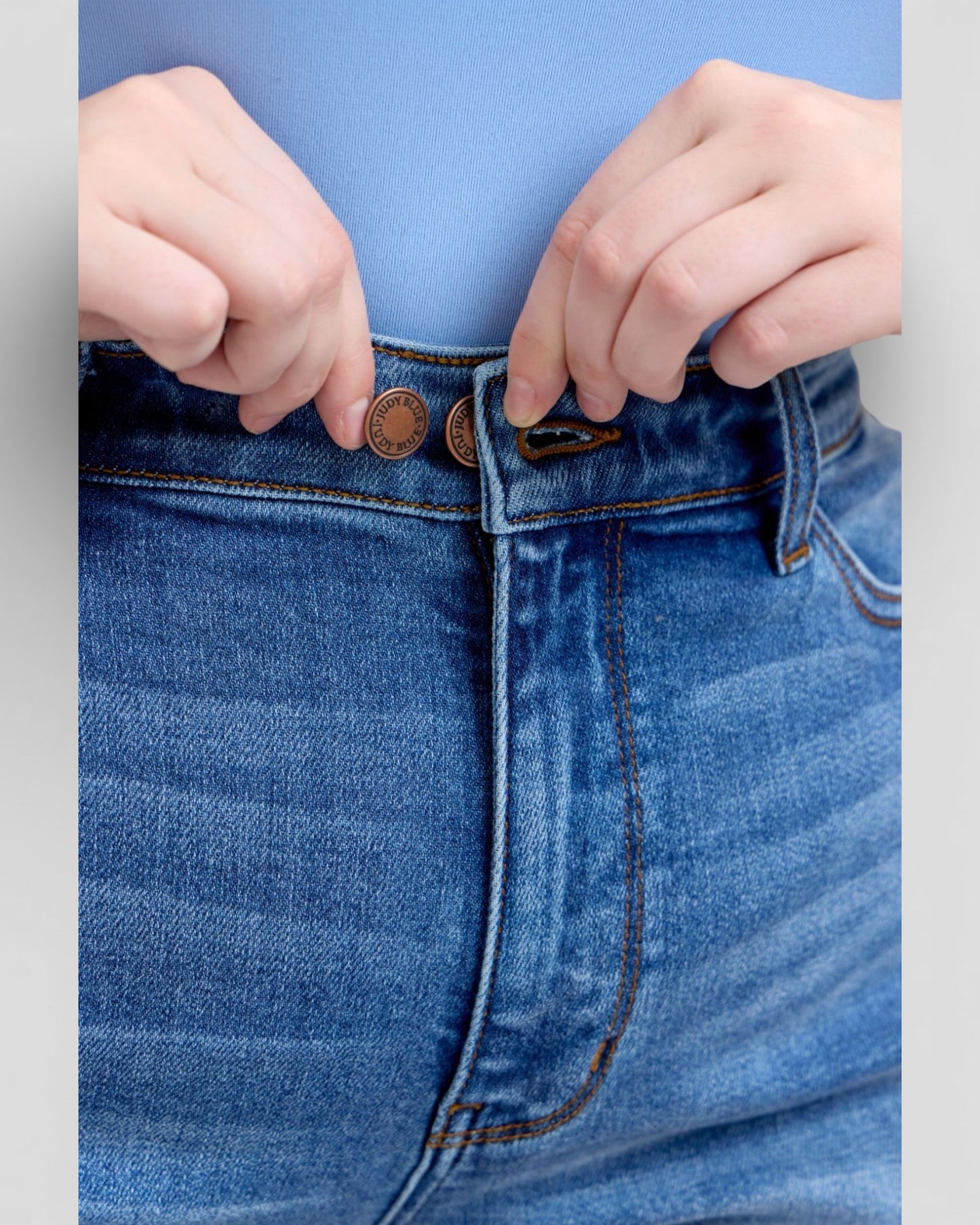 Close-up of blue jeans with a focus on the waistband and buttons.