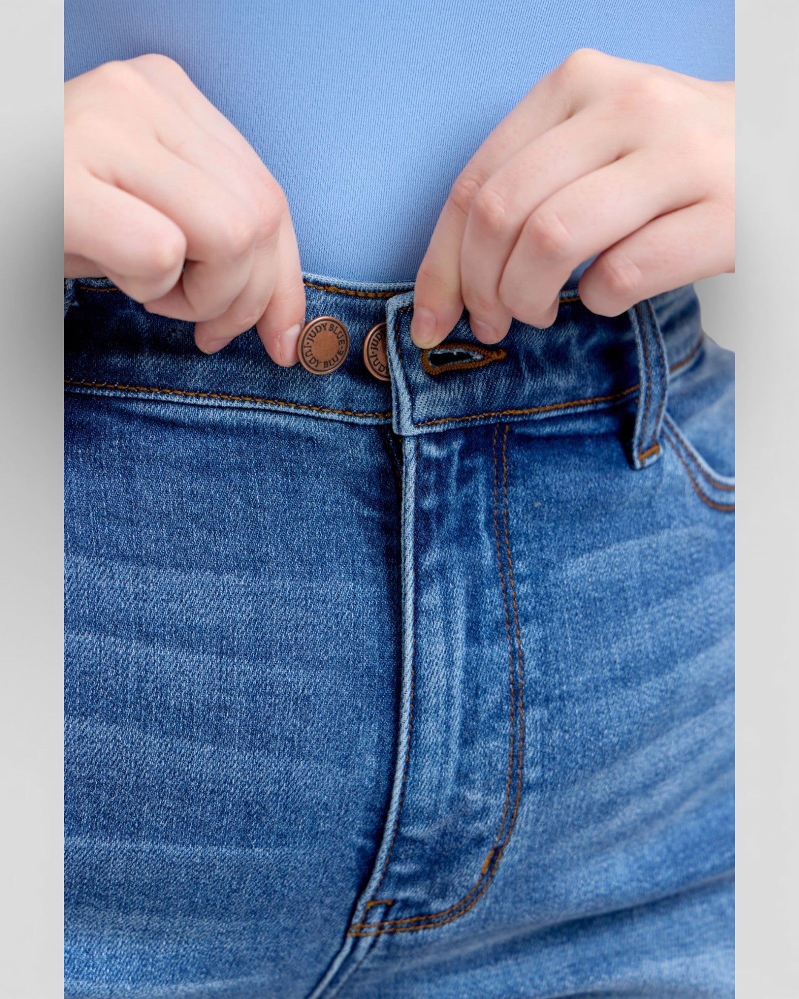 Close-up of blue jeans with a focus on the waistband and buttons.