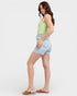 Woman wearing a light green top and denim shorts on a white background