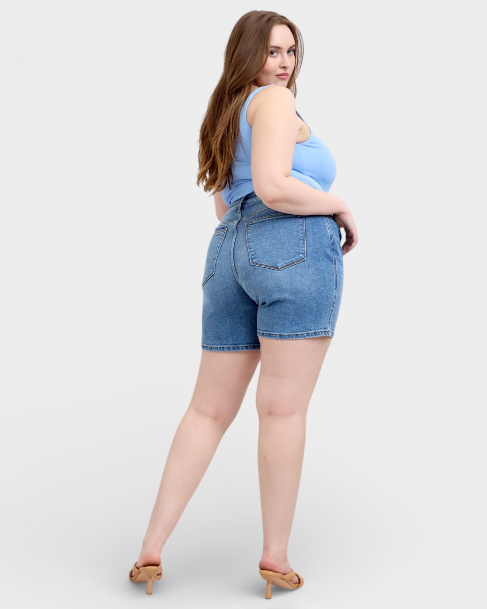 Woman wearing blue denim shorts and a matching top on a white background