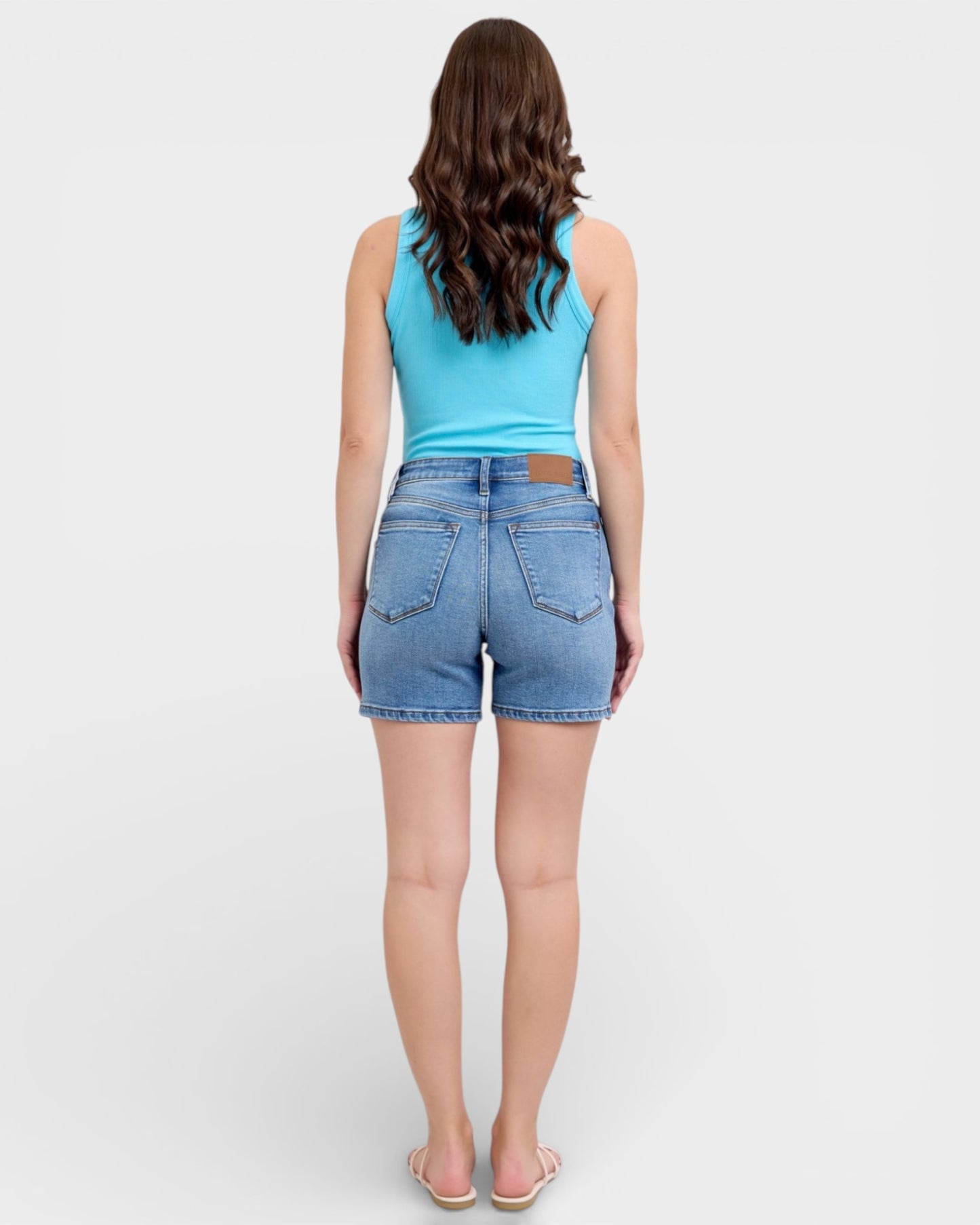 Woman wearing a blue tank top and denim shorts on a white background