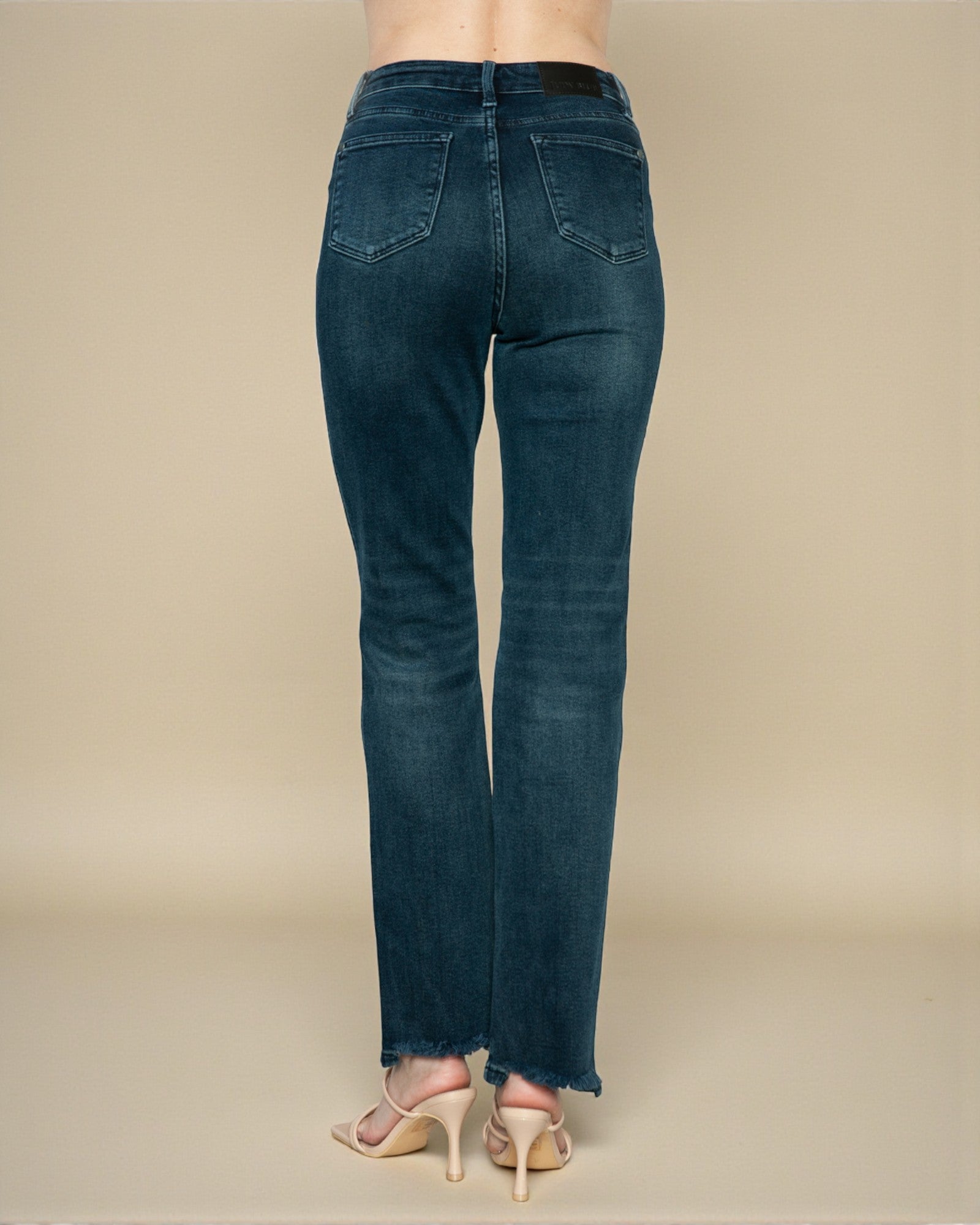 Blue jeans worn by a person on a beige background