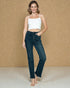 Woman wearing a white top and dark jeans against a beige background