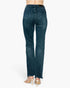 Rear view of a person wearing dark blue denim jeans with a straight-to-flare leg and frayed hems, paired with beige high-heeled sandals against a light gray studio background.
