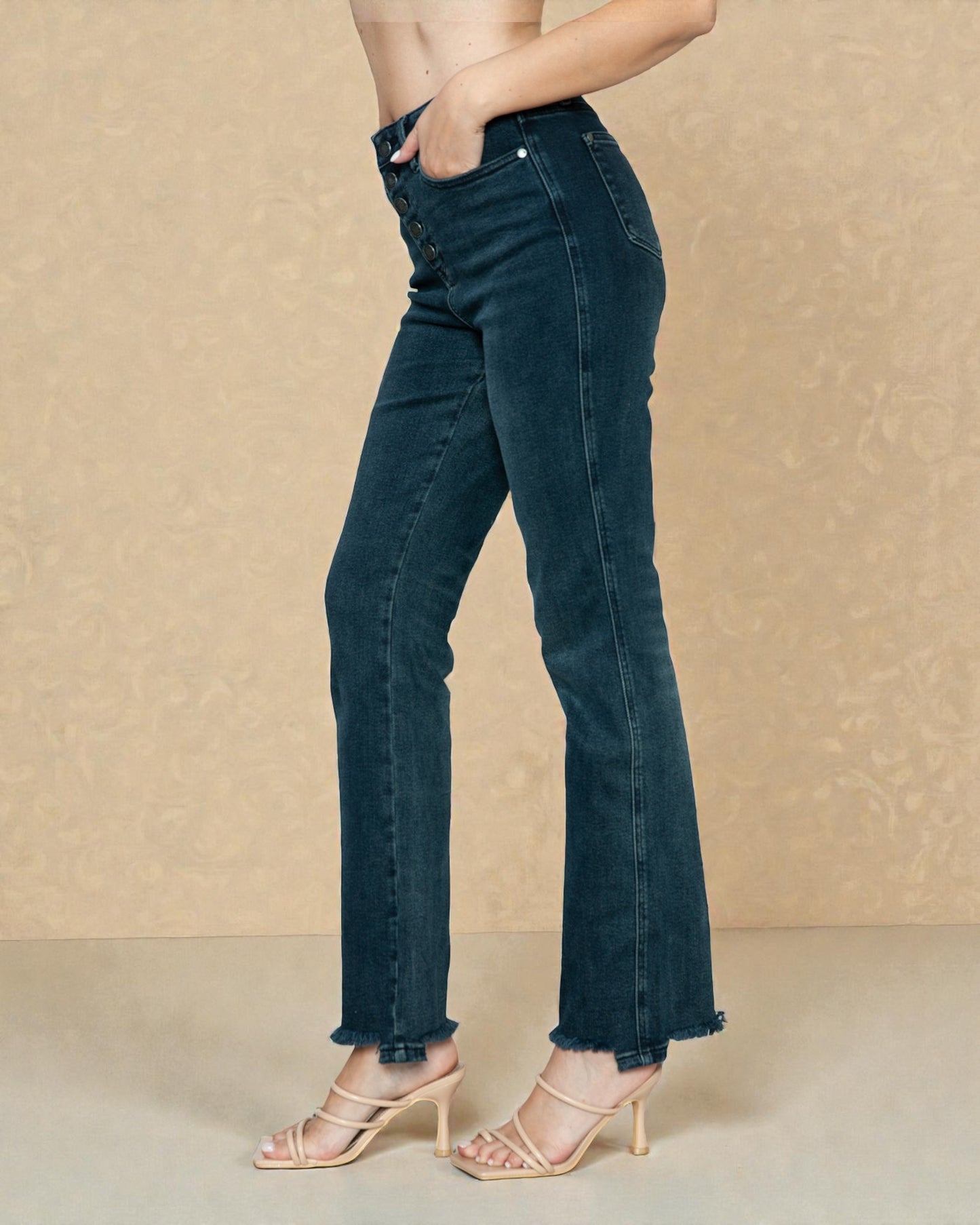 Person wearing dark blue jeans against a beige background