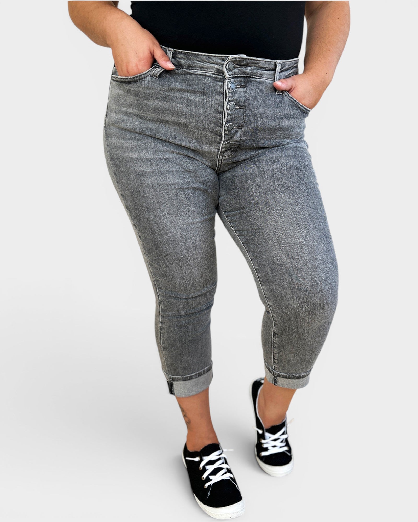 Person wearing light blue jeans and black sneakers on a white background