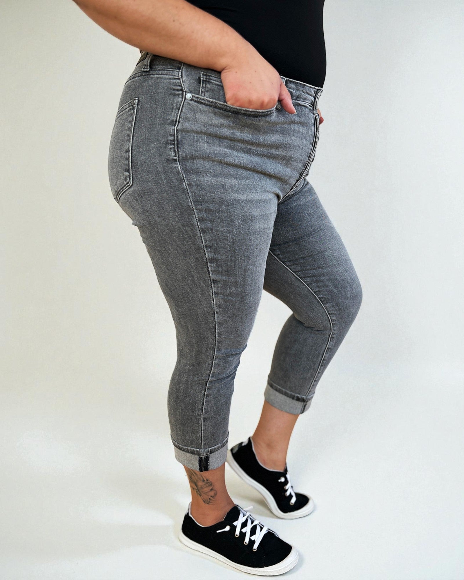 Person wearing gray jeans and black sneakers on a plain background