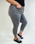 Person wearing gray jeans and black sneakers on a plain background