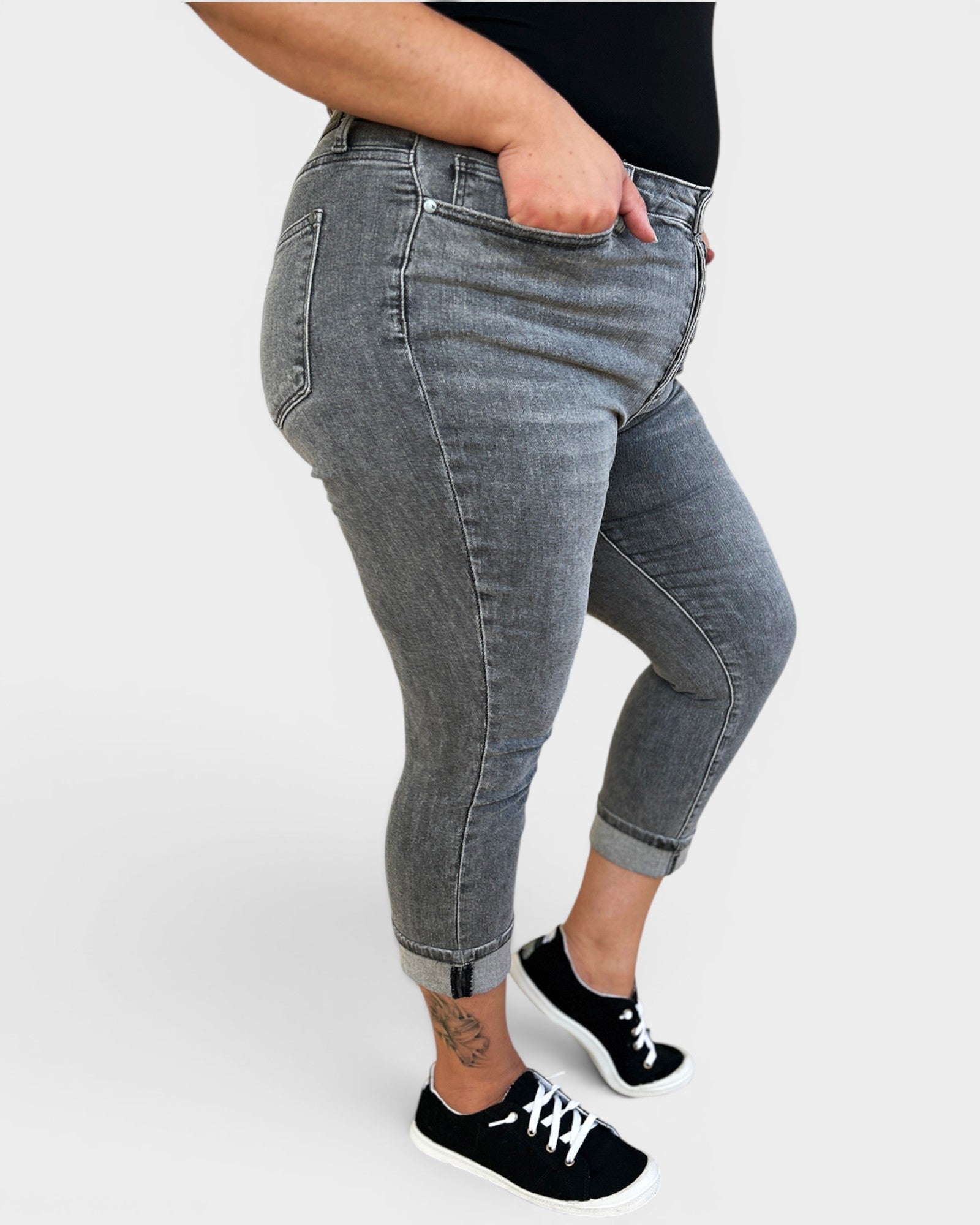 Person wearing gray jeans and black sneakers on a white background
