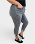 Person wearing gray jeans and black sneakers on a white background
