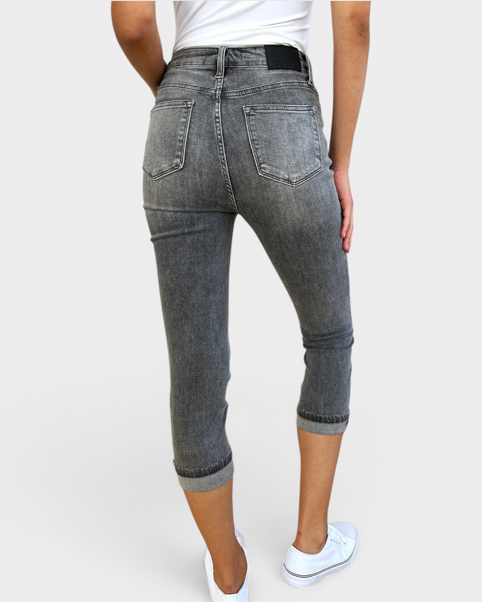 Person wearing gray capri jeans on a white background