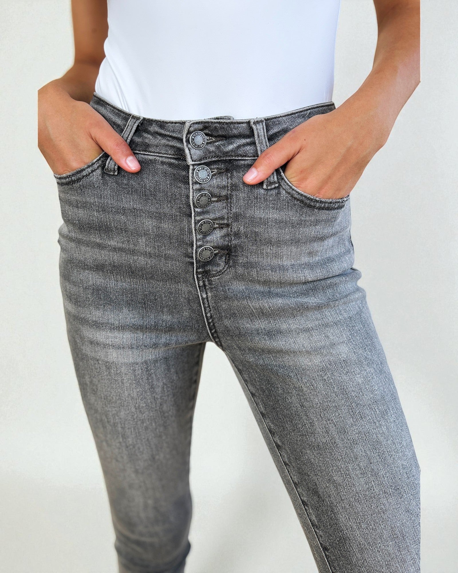 Person wearing gray high-waisted jeans with a plain background