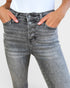 Gray jeans with button details worn by a person on a plain background