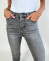 Person wearing gray high-waisted jeans with a plain background