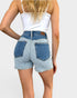 Person wearing light blue denim shorts and a white top on a plain background