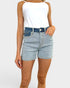 Person wearing light blue denim shorts and a white tank top on a plain background