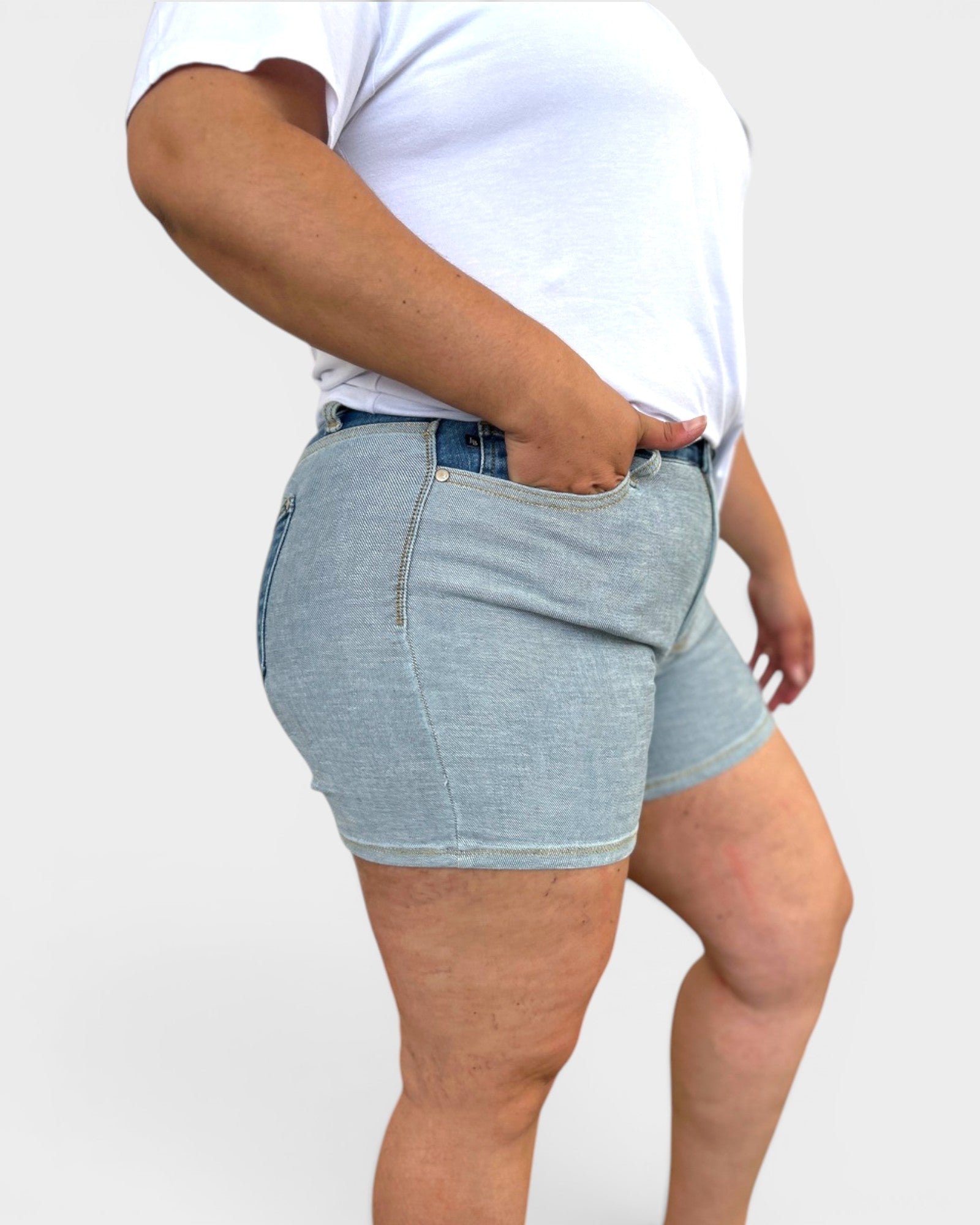 Person wearing light blue denim shorts on a white background