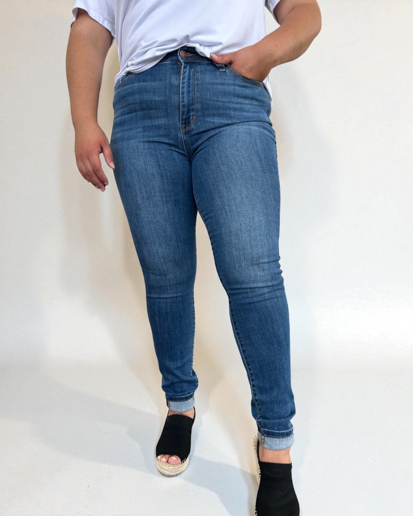 Person wearing blue jeans and a white shirt on a plain background