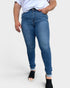 Person wearing blue jeans and a white top on a plain background