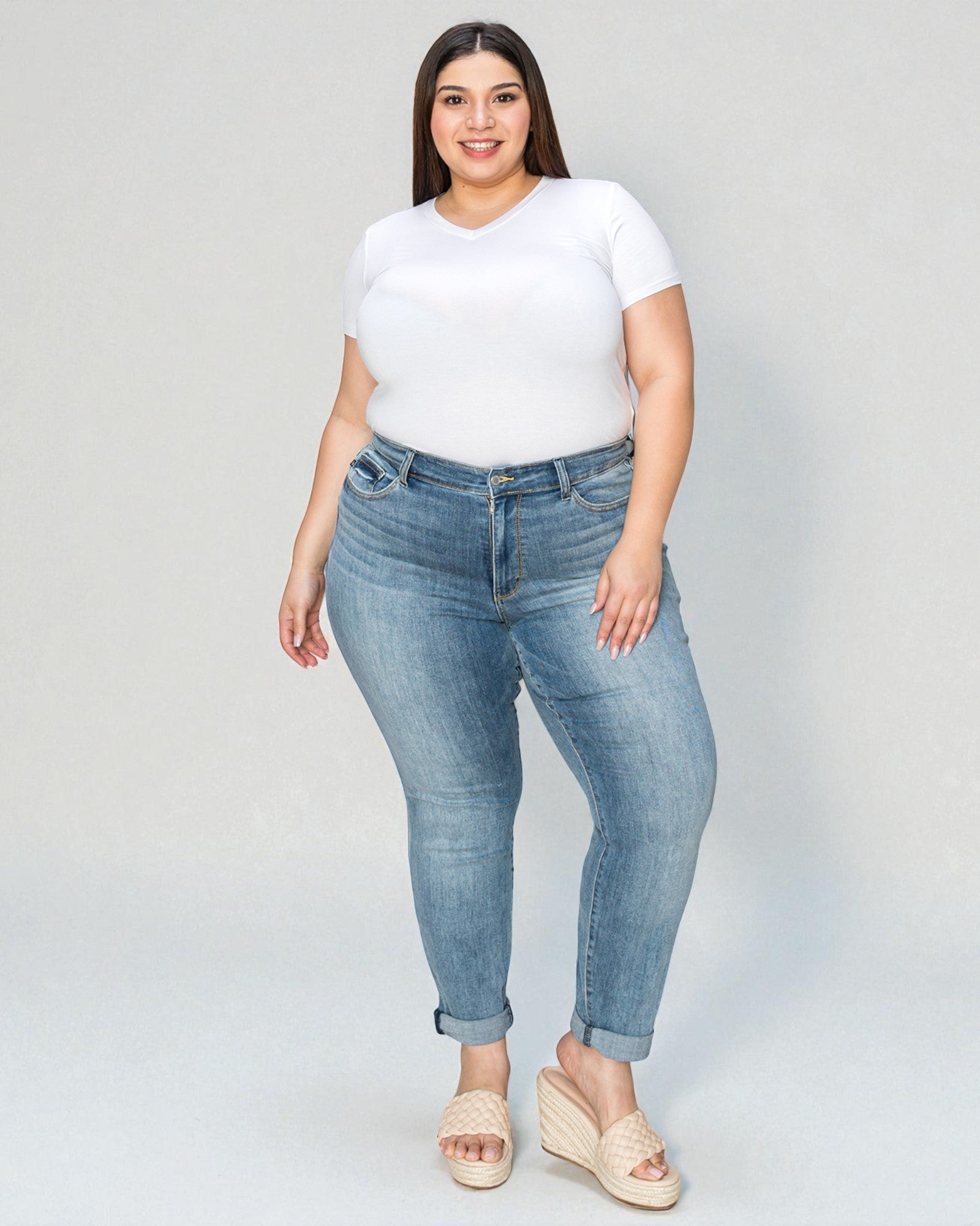 Woman wearing a white t-shirt and blue jeans on a plain background