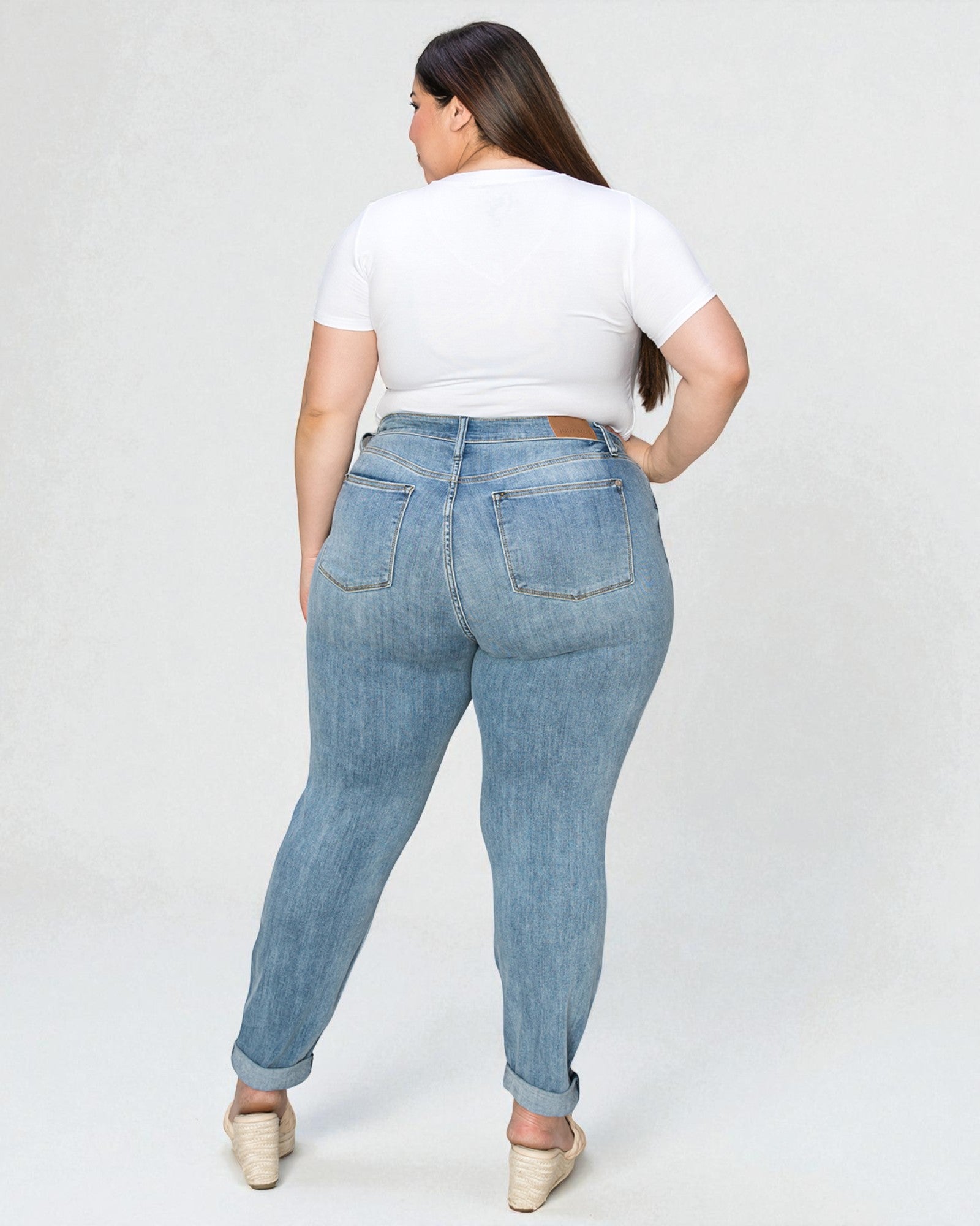 Person wearing light blue jeans and a white t-shirt on a plain background