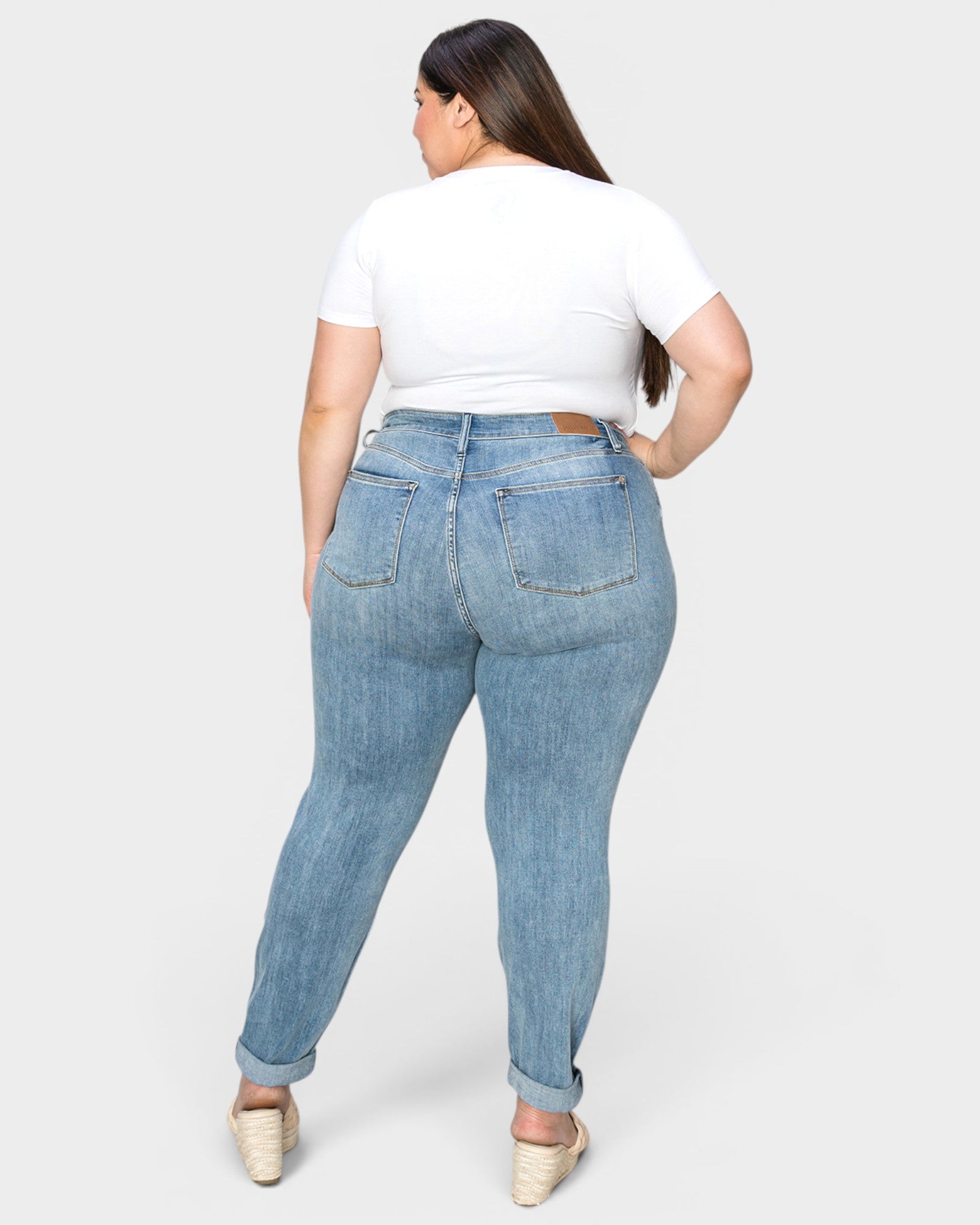 Person wearing light blue jeans and a white crop top on a white background