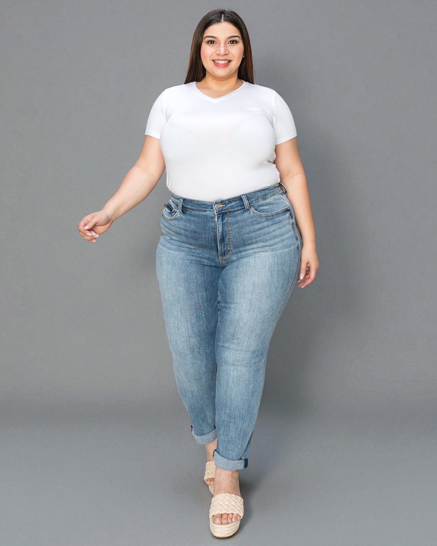 Woman wearing a white t-shirt and light blue jeans on a gray background