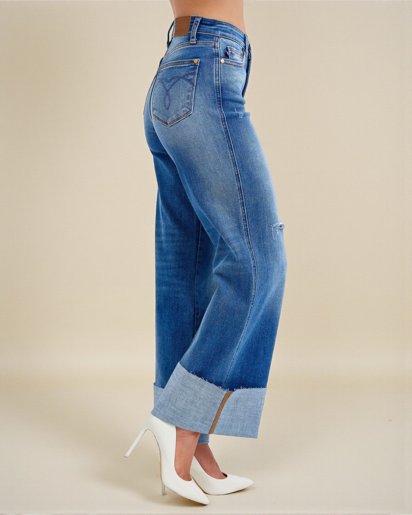 Blue jeans worn by a person on a beige background