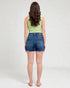 Woman wearing blue denim shorts and a light green top on a white background