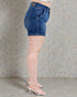 Person wearing blue denim shorts against a gray background