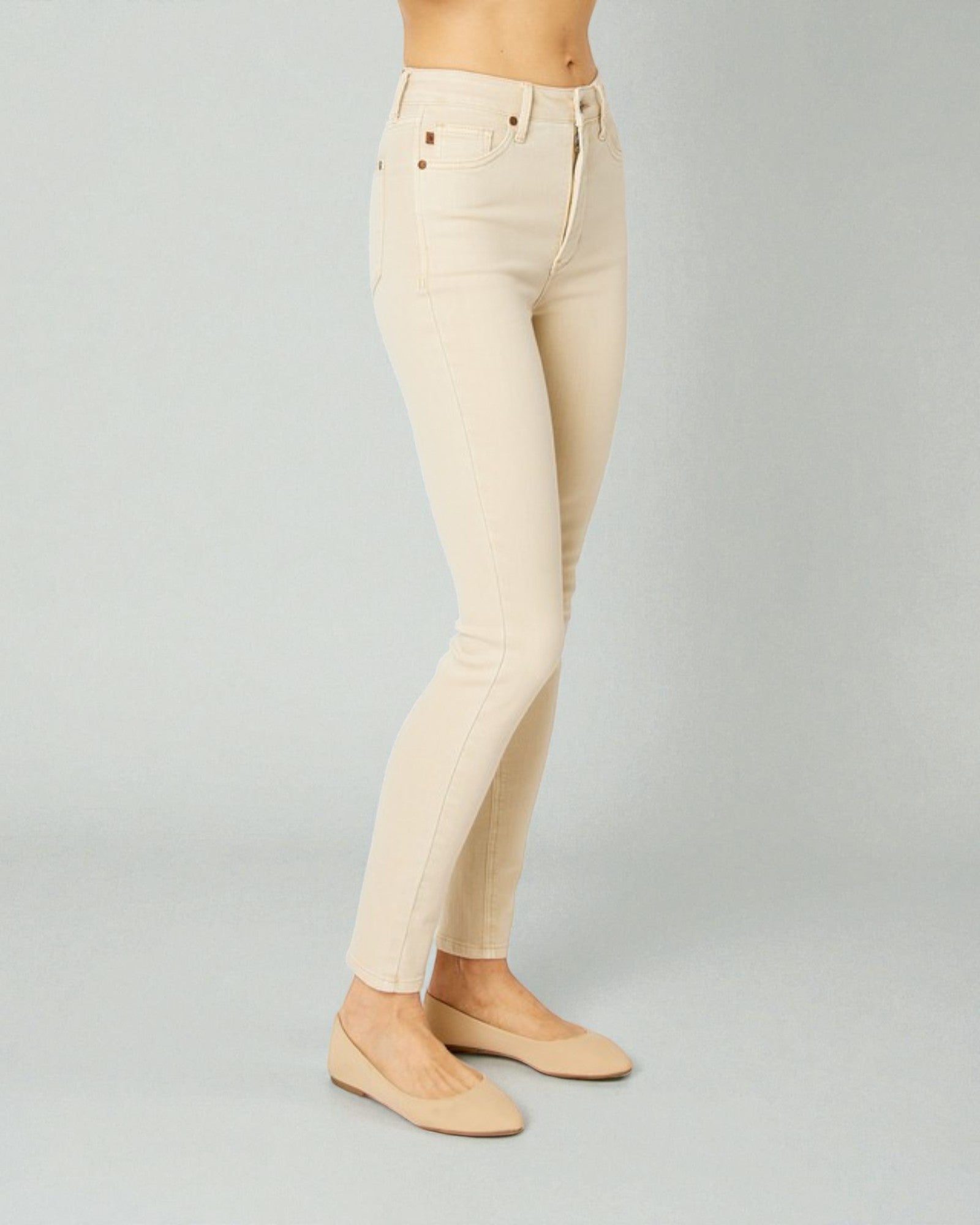 Beige jeans worn by a person on a gray background