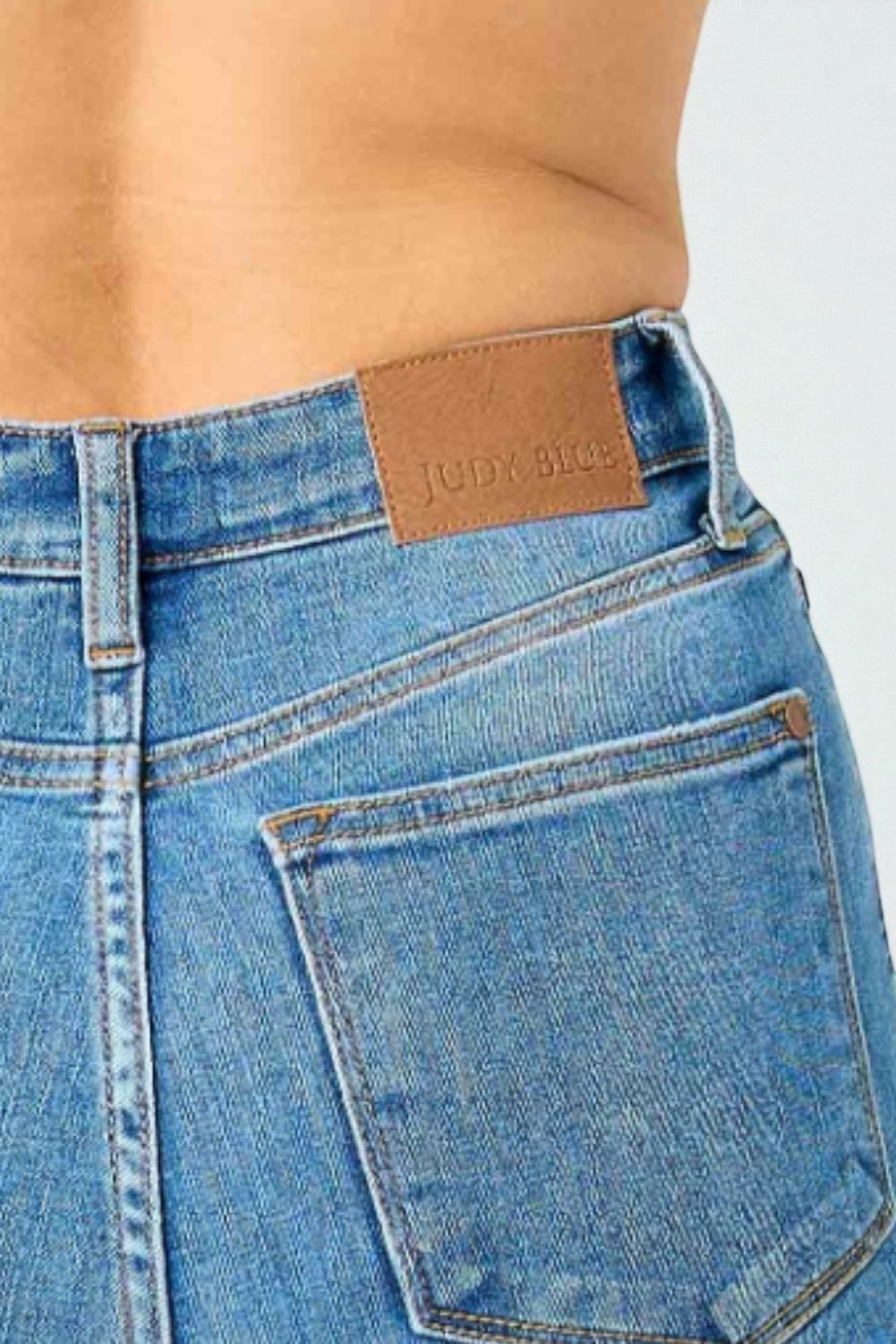 Close-up of blue jeans with a brand label on a light gray background