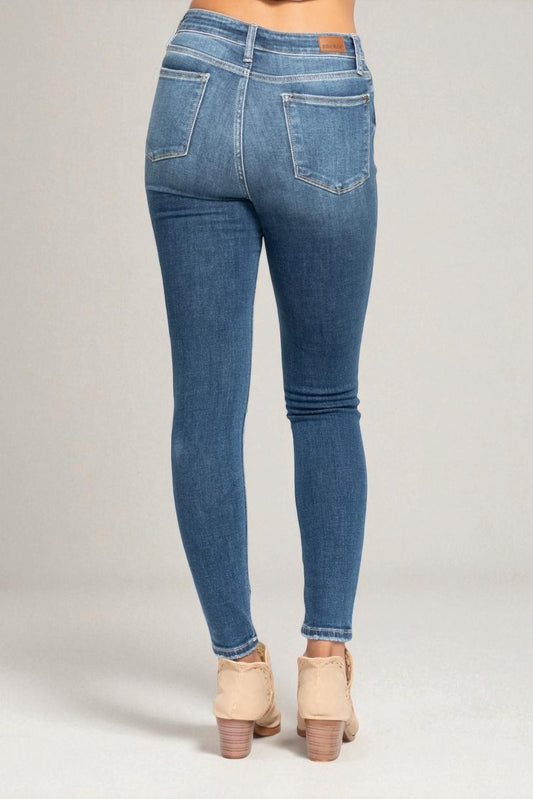 Blue jeans worn by a person on a plain background