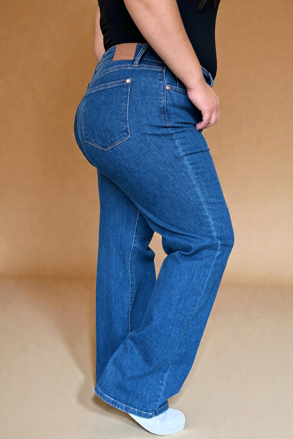 Person wearing blue jeans on a beige background