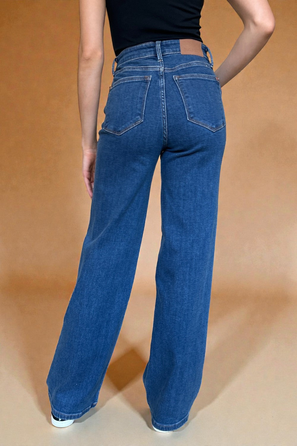 Person wearing blue jeans on a beige background