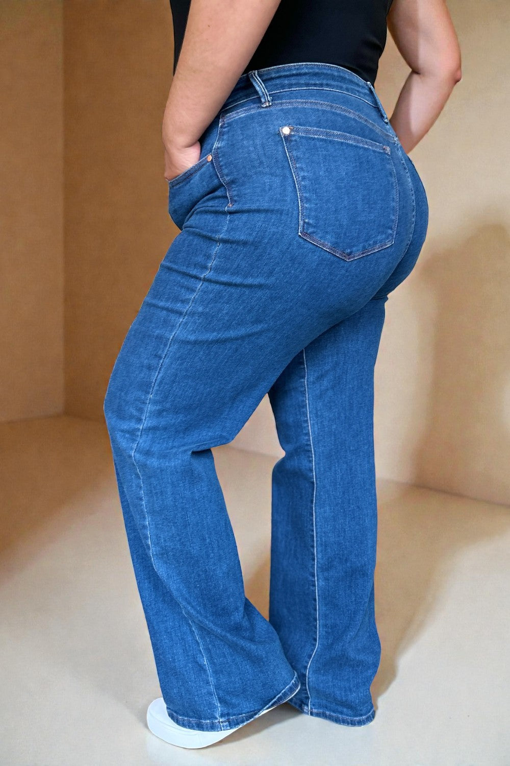 Person wearing blue jeans with a neutral background