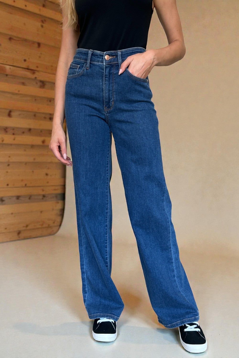 Person wearing blue jeans with a wooden panel background