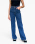 A model wearing a pair of high-waisted, wide-leg blue denim jeans with a black top and black sneakers, shown from the waist down on a light gray background.