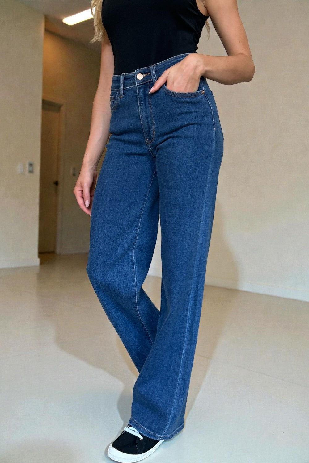 Person wearing blue jeans and a black top in an indoor setting